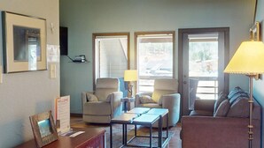 Sala de estar com dois poltronas, um sofá, uma mesa de centro, um abajur e uma placa de boas-vindas.