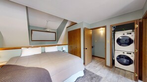 Une chambre à coucher avec un lit, un lave-linge et une porte donnant sur une autre pièce.