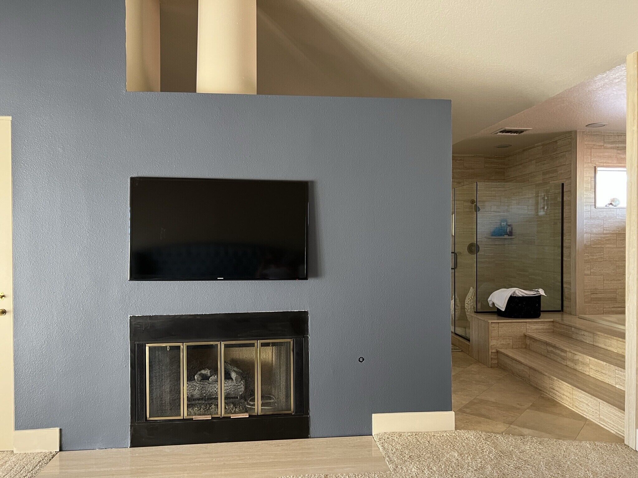 A modern living room with a flat-screen TV mounted above a fireplace.