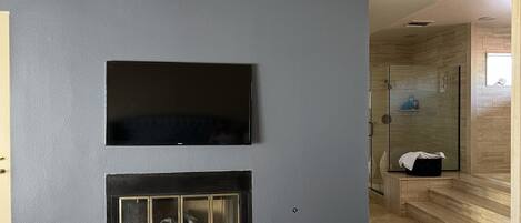 A modern living room with a flat-screen TV mounted above a fireplace.
