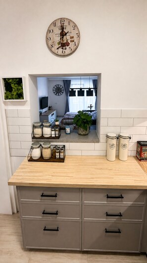 A kitchen with a wooden countertop, a clock, and a view into the adjacent room. - BoRa Apartment First - Villach (Villach)