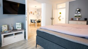 A modern bedroom with a bed, a TV, a desk, and a dining area. - BoRa Apartment First - Villach (Villach)