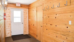 A wooden interior hallway with an exit sign, a door, and a wall-mounted coat rack. - Hide a way in our Lodge that sleeps 18! (Indian River)