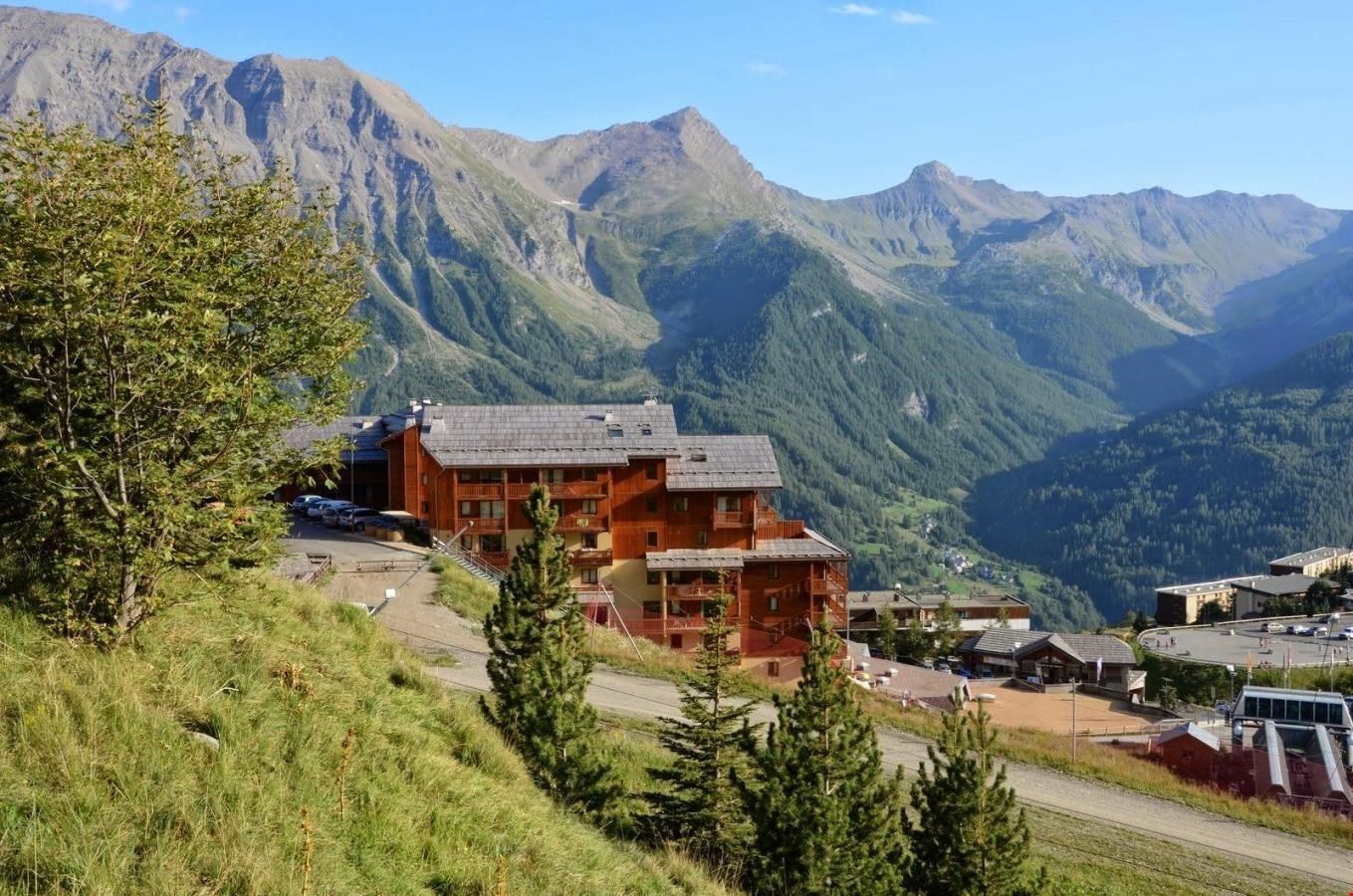 A mountain lodge with a wooden exterior, multiple balconies, and a view of the surrounding mountains.