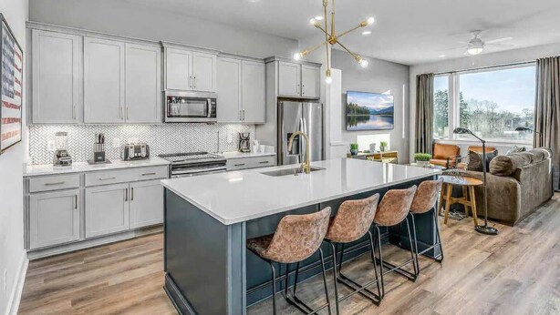 A modern kitchen with a central island, bar stools, a dining area with a table and chairs, and a large window with a view. - 2 Premier Nashville Homes • Sleeps 24 • Rooftops (Nashville)