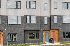 Un immeuble résidentiel à plusieurs étages, doté d’une architecture moderne, caractérisé par une combinaison de briques et de panneaux pour les façades, de grandes fenêtres et un toit plat.