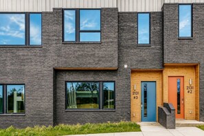 Un immeuble moderne à plusieurs étages, doté de grandes fenêtres et d’une façade en briques.