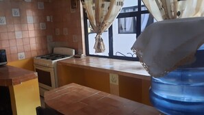 Una cocina compacta con microondas, estufa y salpicadero de azulejos.