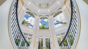 A grand staircase with multiple levels, large arched windows, and a view of the outdoors. - Private Luxury Villa in Kihei. Just moments walk to the beach. 10/10 reviews! (Kihei)