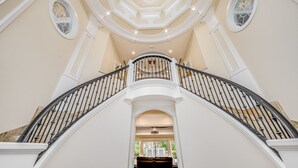A grand staircase with a balustrade, leading to a landing with a chandelier. - Private Luxury Villa in Kihei. Just moments walk to the beach. 10/10 reviews! (Kihei)