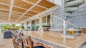 A covered outdoor bar area with a long counter, multiple chairs, and a grill. - Private Luxury Villa in Kihei. Just moments walk to the beach. 10/10 reviews! (Kihei)