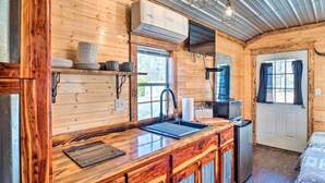 Ein Interieur einer Holzhütte mit Küchenzeile, einschließlich Spüle, Schränken und einem Kühlschrank.