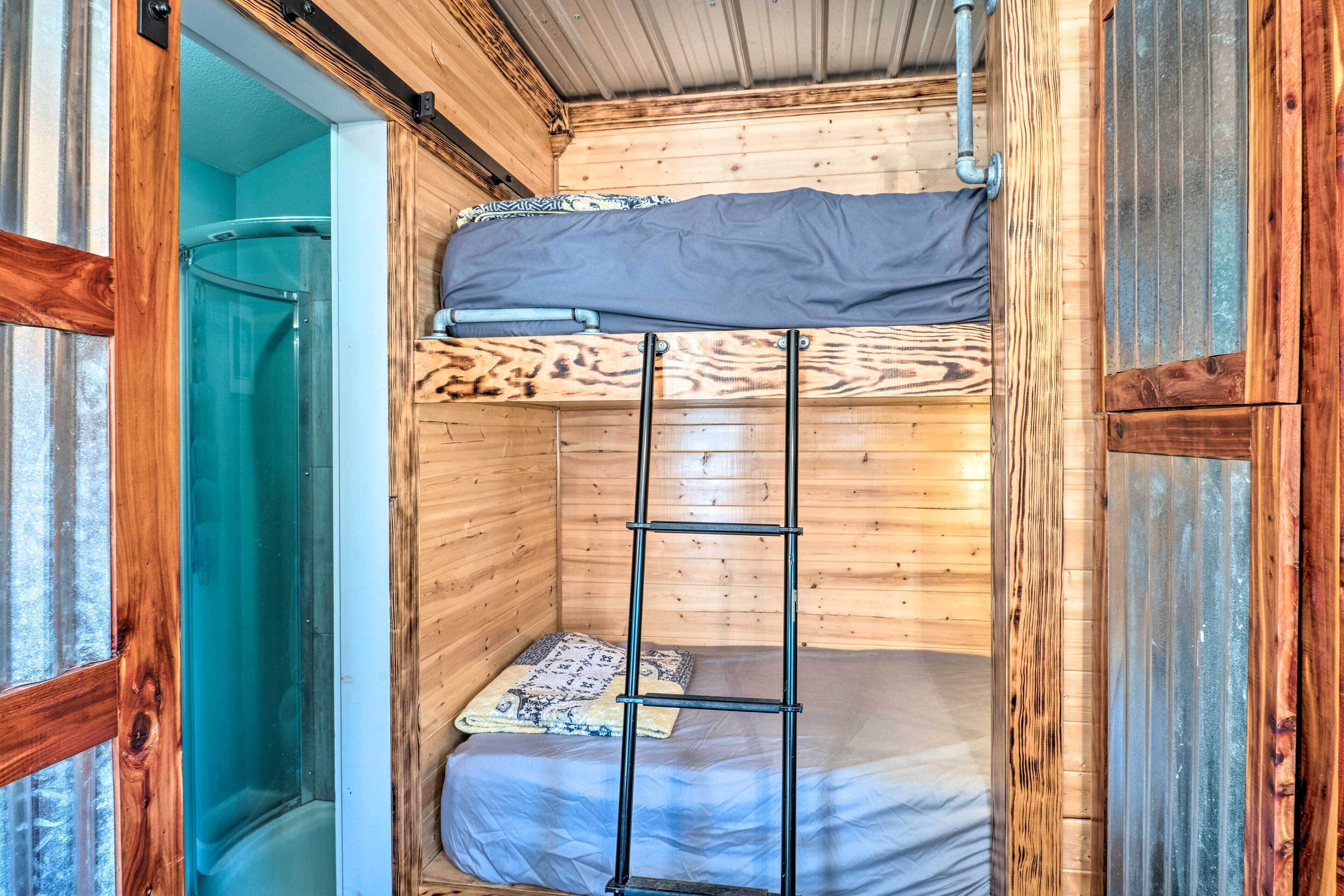 Een compact houten vakantiehuisje met een stapelbed, een ladder en een klein raam.