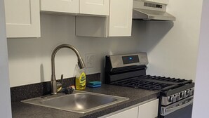 Une cuisine avec des meubles blancs, un lave-vaisselle en acier inoxydable, une cuisinière à gaz et un four encastré.