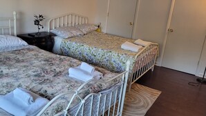Une chambre avec deux lits simples, une table de chevet, une lampe et une armoire.