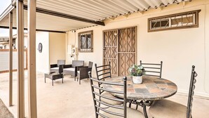 A covered patio area with a round table and chairs, a potted plant, and a decorative wall panel. - 5 Mi to Pima Air & Space Museum: Sunny Tucson Gem (Tucson)