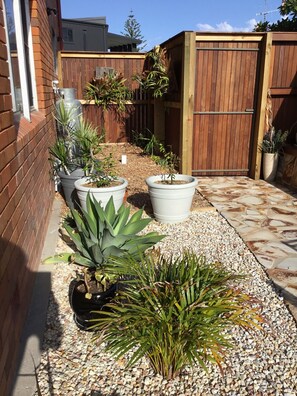 Stroll through a serene garden area with potted plants and a stone patio.