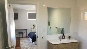 A modern bathroom with a white sink, wooden cabinet, and a large mirror. - “Mona’s On Rockpool” - Waterfront heaven (Tuncurry)