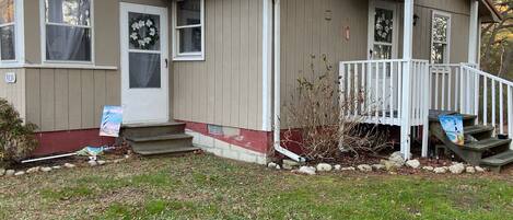 A small, single-story house with a front porch, a mailbox, and a door with a wreath.