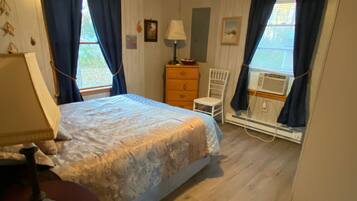 Een slaapkamer met een bed, een kaptafel, een stoel en een kleine tafel met een lamp.