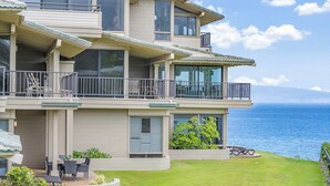 Un edificio residenziale a più piani con balconi, una zona patio con mobili da esterno e vista sull'oceano.