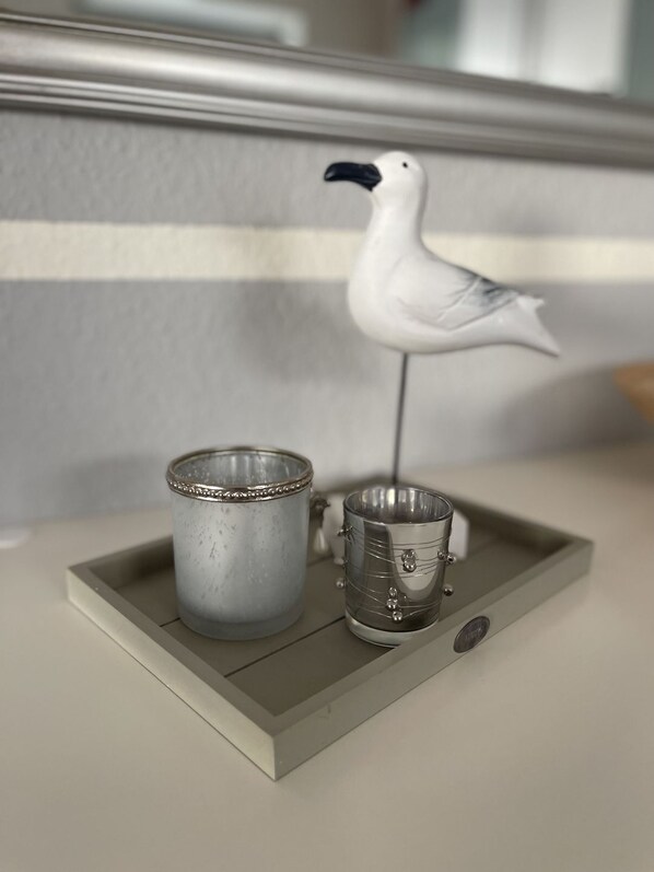 Ett bricka med två metallmuggar och en dekorativ fågelstatyett.