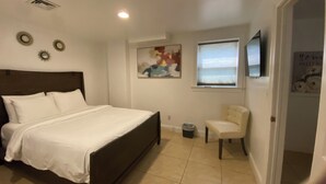 A bedroom with a bed, a chair, a painting, and a window. - Lovely Basement with 2 Bedrooms and Kitchen (Huntington)