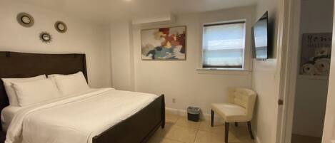 A bedroom with a bed, a chair, a painting, and a window.