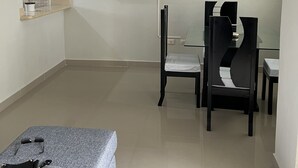 A modern living room with a flat-screen TV mounted on the wall, a dining area with a glass table and chairs, and a sofa with a grey cover. - LOVELY TWO BEDROOMS , TWO BATHROOMS IN HIGUEY (Higüey)