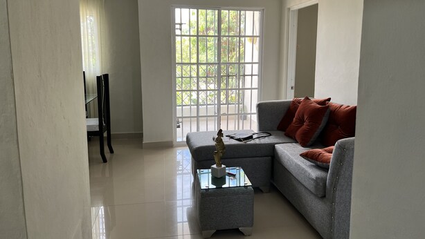 A modern living room with a grey sofa, a glass coffee table, and a ceiling light fixture. - LOVELY TWO BEDROOMS , TWO BATHROOMS IN HIGUEY (Higüey)