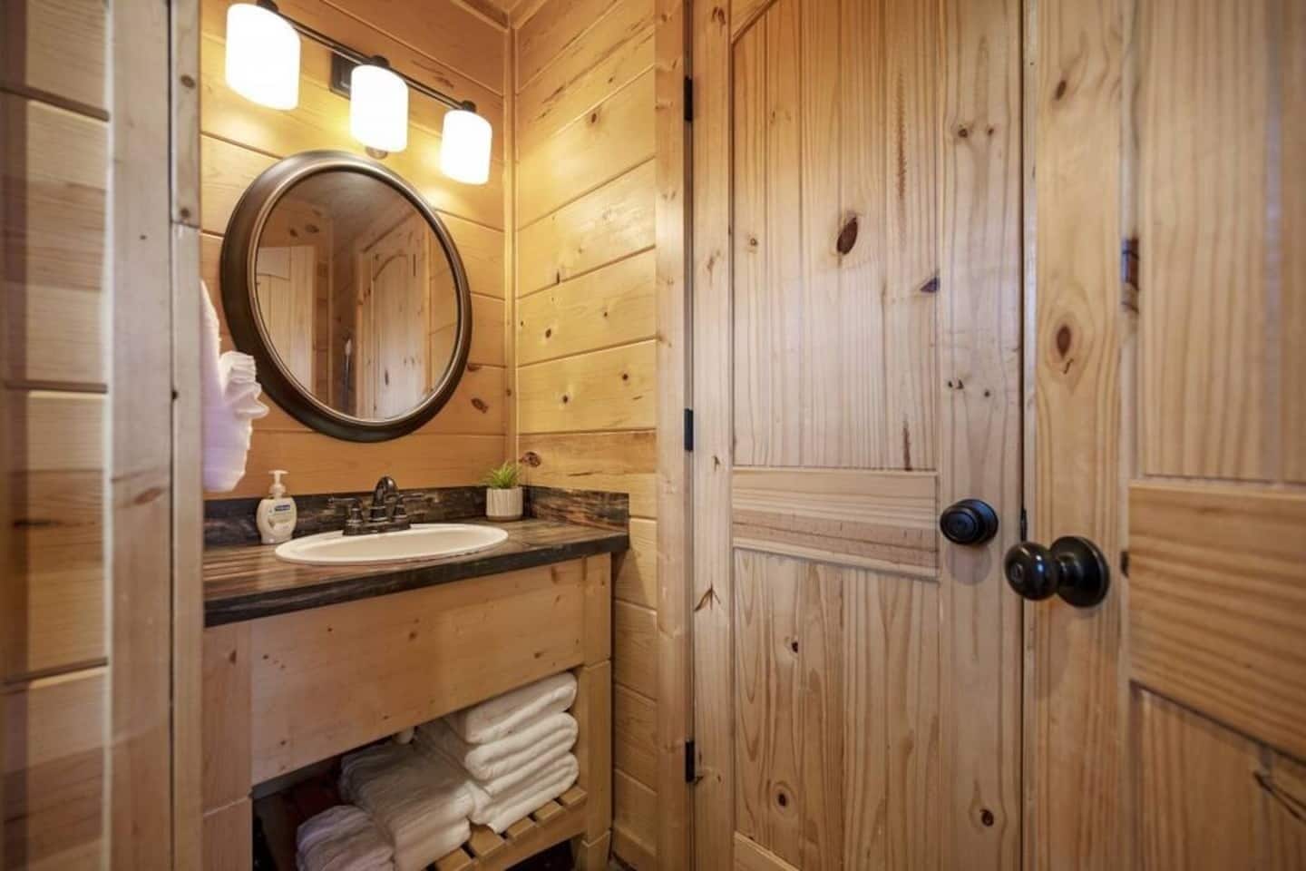 Un baño de madera con un espejo redondo, un lavamanos y un perchero para toallas.