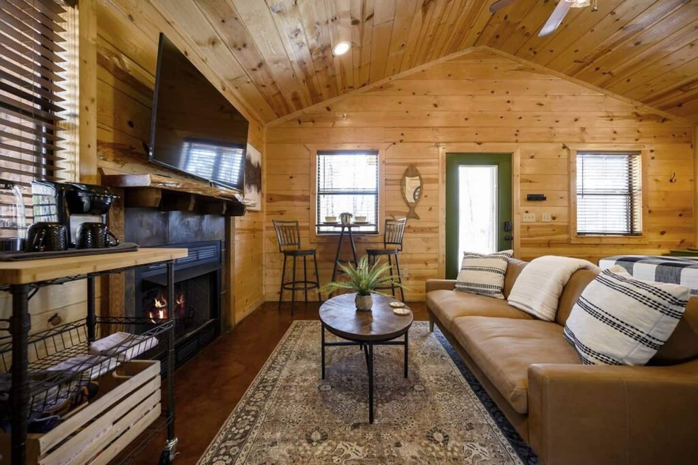 L’intérieur chaleureux d’un chalet avec une cheminée, des murs en bois, un canapé et un coin repas.