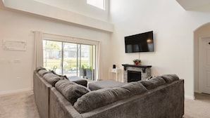 Un salon moderne avec un canapé d’angle, une cheminée et un téléviseur fixé au mur.