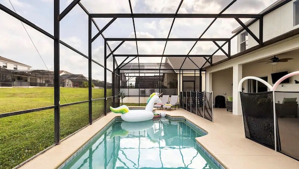 Une piscine intérieure avec un cygne flottant, des murs en verre et une vue sur les environs.
