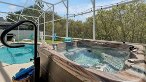 A hot tub with a glass enclosure, a pool, and a covered patio area. - Modern Disney Villa w/ Pool, Hot Tub, Game Room & Themed Kids Rooms! (Kissimmee)