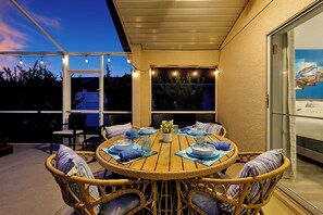 A covered outdoor dining area with wicker chairs and a round table set for four. - Modern Disney Villa w/ Pool, Hot Tub, Game Room & Themed Kids Rooms! (Kissimmee)