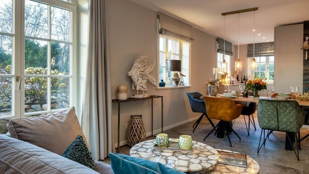 Un salon moderne avec un canapé, un coin repas avec des chaises, une cuisine avec une table à manger et de grandes fenêtres.