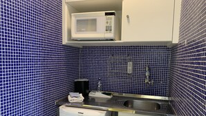 A compact kitchenette with a microwave, sink, and small refrigerator. - Akile B. Ribeiro (São Paulo)
