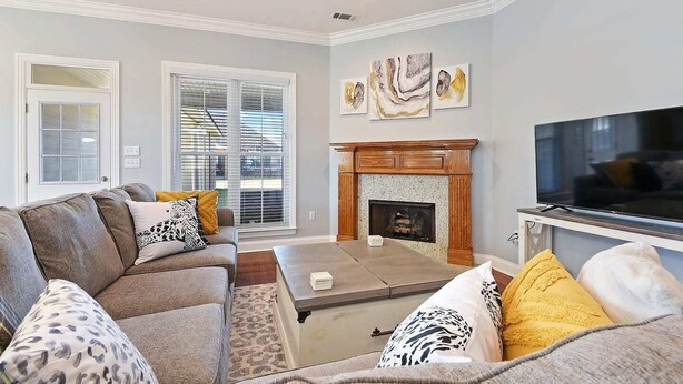 A living room with a fireplace, a television, and a sofa with patterned cushions. - Just minutes from LSU, SU & Downtown Baton Rouge! (Addis)