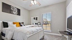 A bedroom with a bed, a ceiling fan, a TV, and a window with blinds. - Just minutes from LSU, SU & Downtown Baton Rouge! (Addis)
