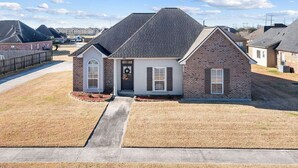 A single-story house with a brick facade, a front porch, and a small front yard. - Just minutes from LSU, SU & Downtown Baton Rouge! (Addis)