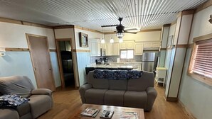 Een ruime woonkamer met een houten salontafel, twee banken en een keuken op de achtergrond.