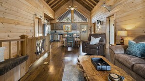 A wooden cabin interior with a dining area, a sofa, and a fireplace. - NEW! Private Mountain Cabin in Gated Community w/ Mtn Views, Hot Tub & Game Room (Morganton)