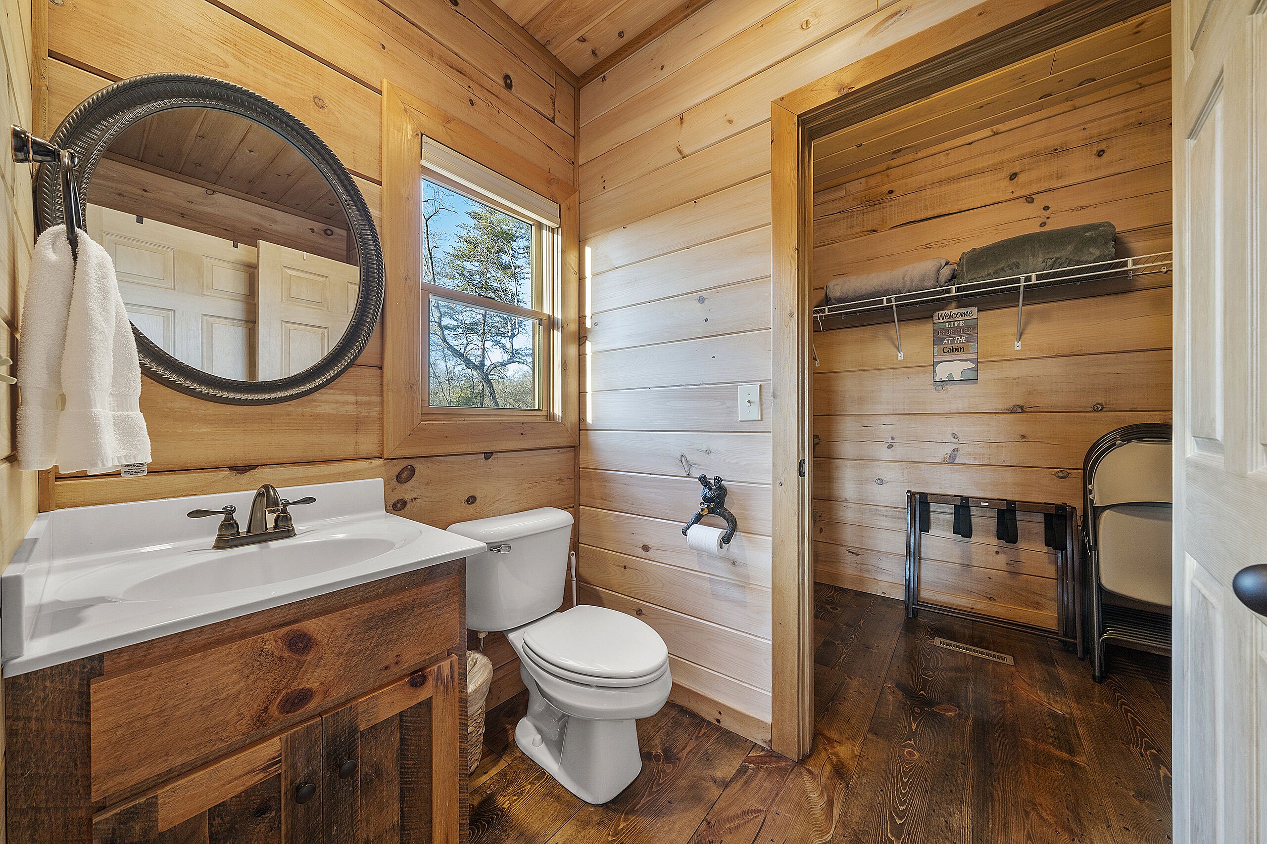 A wooden cabin bathroom with a sink, toilet, and a mirror.