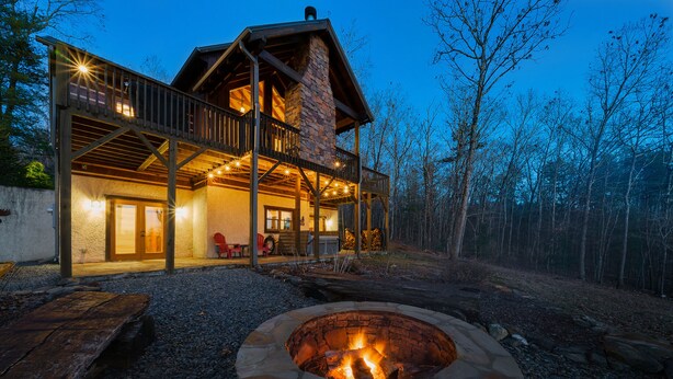 A lodge with a stone fireplace, wooden deck, and a large porch area. - NEW! Private Mountain Cabin in Gated Community w/ Mtn Views, Hot Tub & Game Room (Morganton)