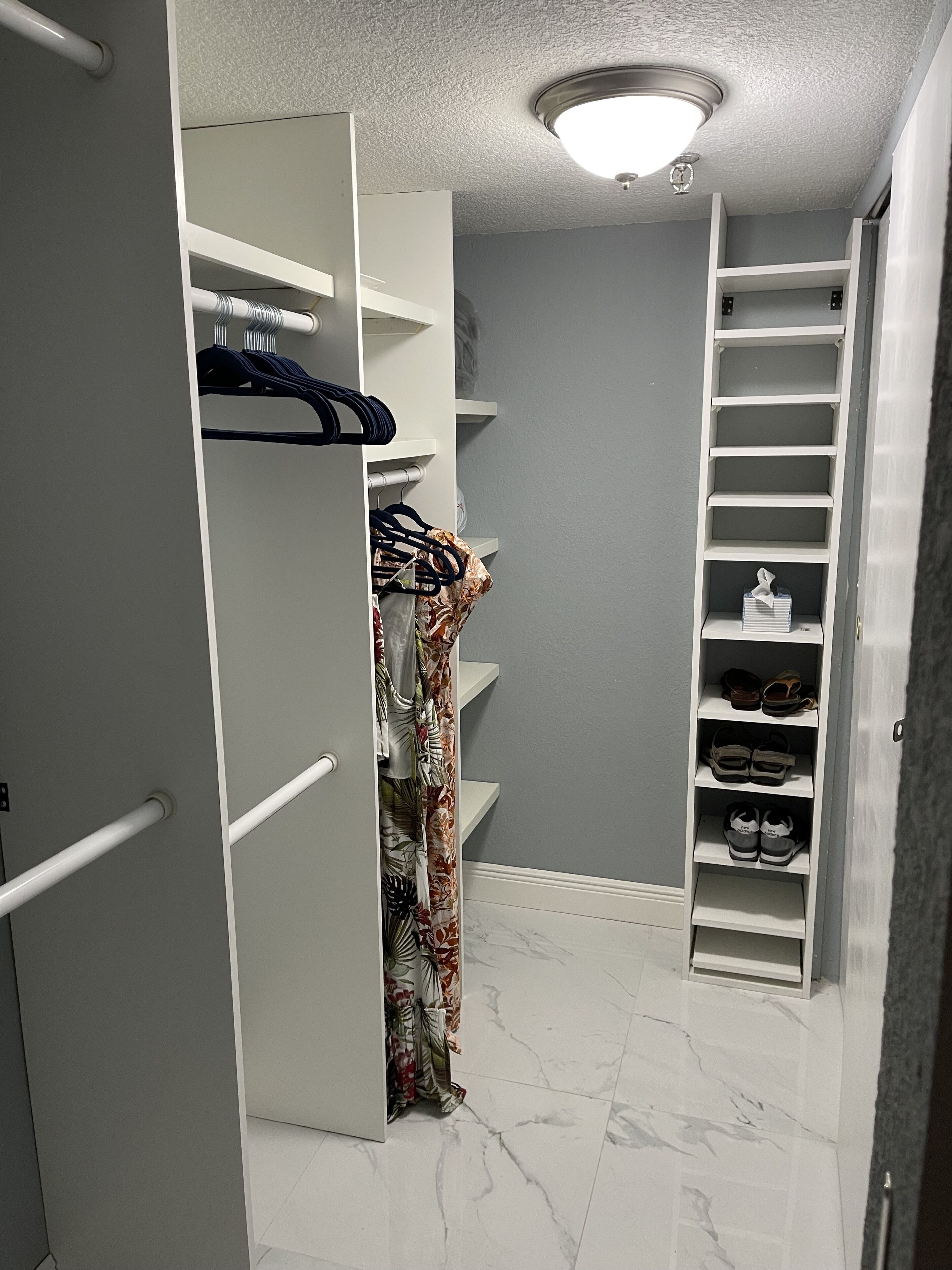 Un vestidor con estanterías blancas, una barra para colgar ropa y un zapatero.