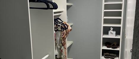 Un vestidor con estanterías blancas, una barra para colgar ropa y un zapatero.