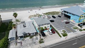Un hôtel situé sur la côte, doté d’un parking, offrant une vue sur la plage et dont le bâtiment est surmonté d’un toit bleu.
