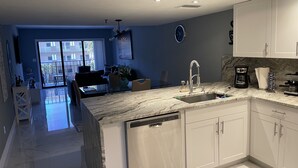 Une cuisine moderne avec des meubles blancs, un plan de travail en marbre et un lave-vaisselle.