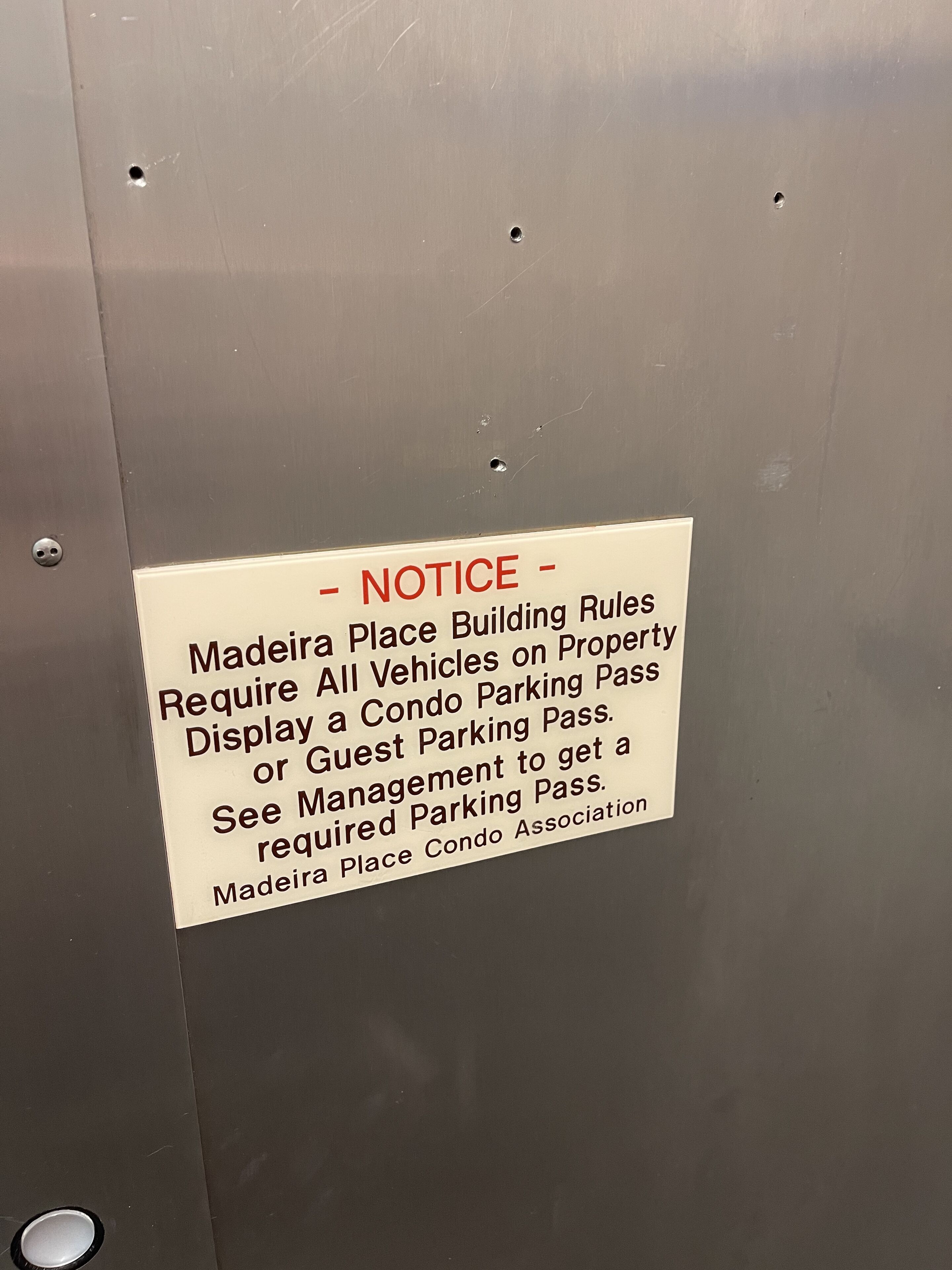 Een bericht op een metalen oppervlak met parkeerregels voor een appartementencomplex.